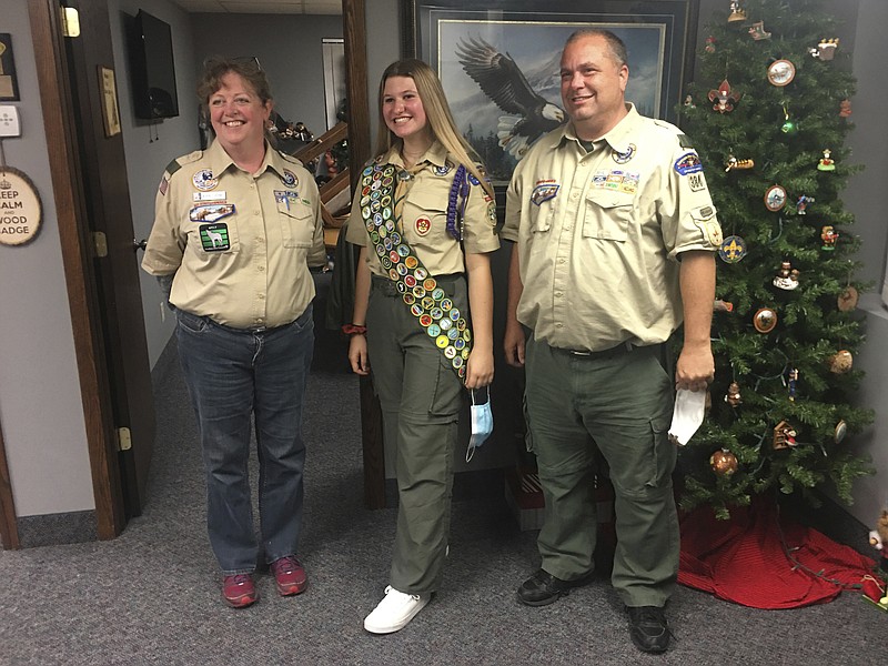 This Oct. 1, 2020 photo provided by Edmund Tunney shows his daughter, Isabella, center, with Bev Verweg, her scoutmaster, and Brian Reiners, the scoutmaster of the corresponding linked boy troop, in Edina, Minn. In February 2021, at age 16, Tunney will be one of nearly 1,000 girls and young women honored by the Boy Scouts in a virtual celebration of the inaugural class of female Eagle Scouts. It’s a major milestone, given the hallowed stature of a rank that has been attained over more than a century by astronauts, admirals, U.S. senators and other luminaries. (Edmund Tunney via AP)