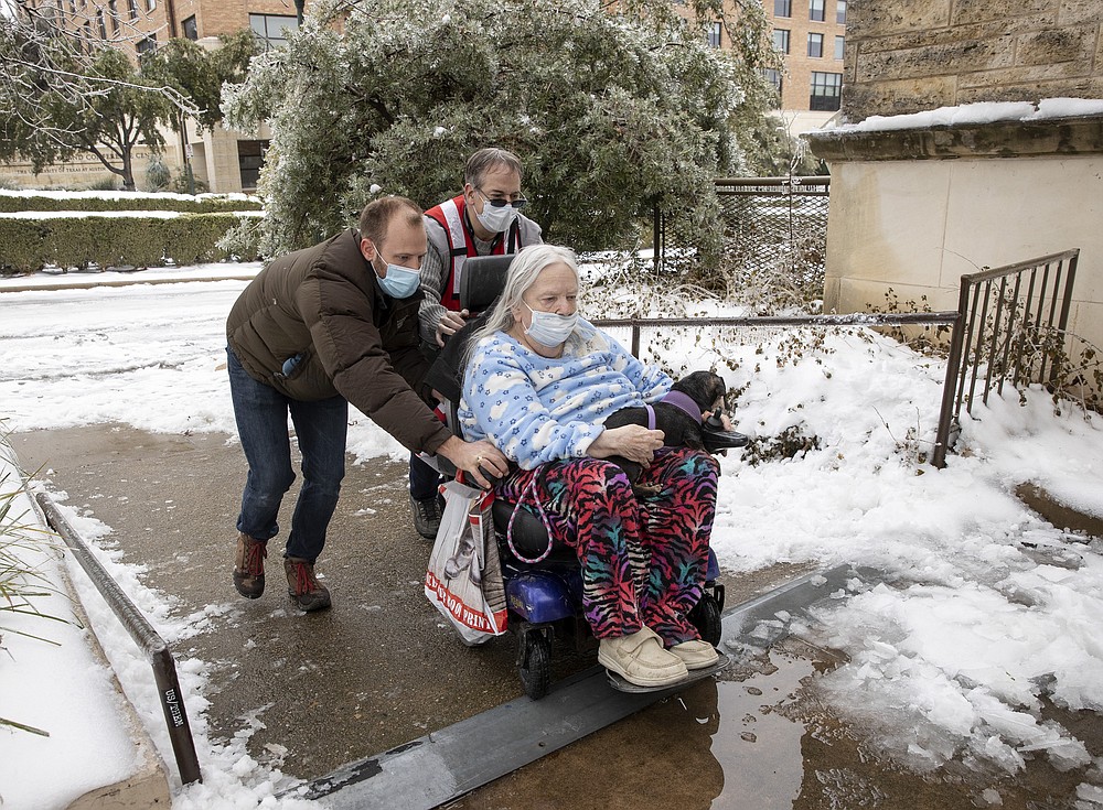 FILE - In this Feb. 17, 2021 file photo, Dori Ann Upchurch is helped by Austin Disaster Relief Network volunteer Cody Sandquist, left, and a Red Cross volunteer to a warming station in Austin, Texas, after being evacuated from her home. With the snow and ice clearing in Texas after the electricity was cut to millions as temperatures plunged as people struggled to stay warm in their unheated homes. (Jay Janner/Austin American-Statesman via AP, File)