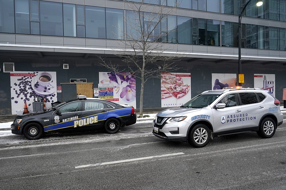 A security vehicle drives by a Baltimore police cruiser parked near a building while officers check on a call, Thursday, Feb. 18, 2021, in Baltimore. A package of police reforms in Maryland this year prompted by the death of George Floyd includes a proposed repeal of the Law Enforcement Officers Bill of Rights, the first-in-the-nation law implemented in 1974 that has been replicated in other states. (AP Photo/Julio Cortez)