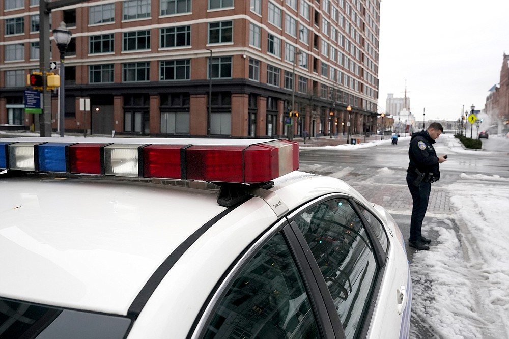 A Baltimore police officer checks his cell phone near his cruiser, Thursday, Feb. 18, 2021, in Baltimore. A package of police reforms in Maryland this year prompted by the death of George Floyd includes a proposed repeal of the Law Enforcement Officers Bill of Rights, the first-in-the-nation law implemented in 1974 that has been replicated in other states. (AP Photo/Julio Cortez)
