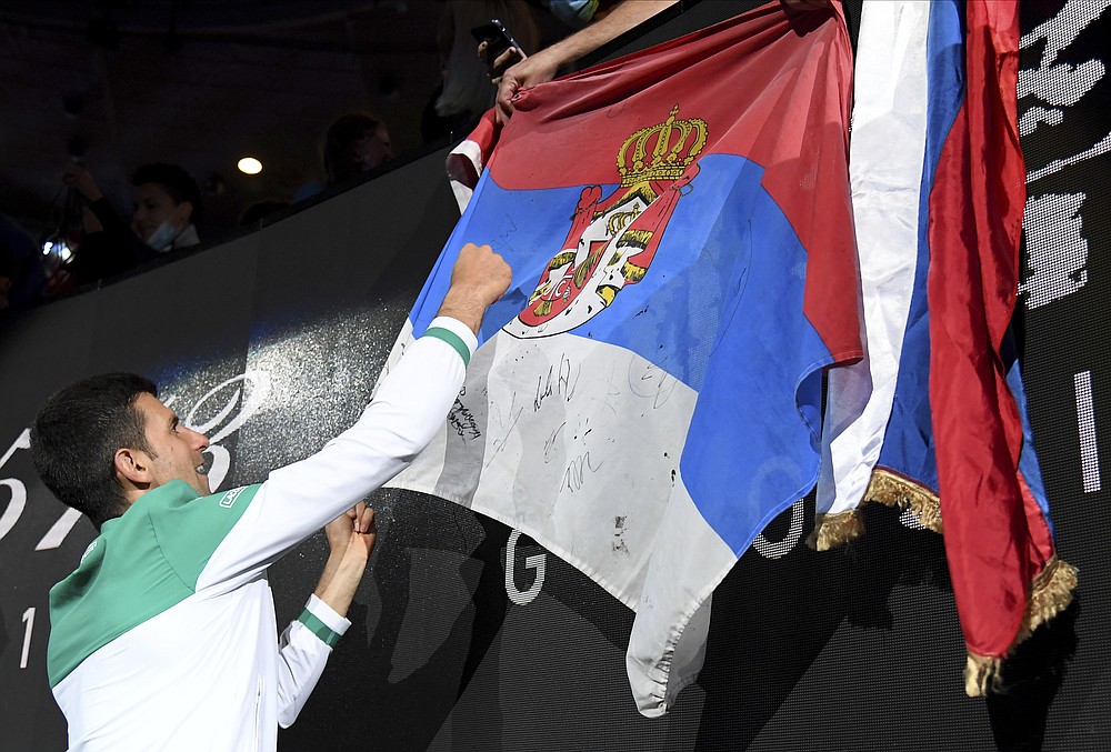 Serbia's Novak Djokovic signs autographs after defeating Russia's Daniil Medvedev during the men's singles final at the Australian Open tennis championship in Melbourne, Australia, Sunday, Feb. 21, 2021.(AP Photo/Andy Brownbill)