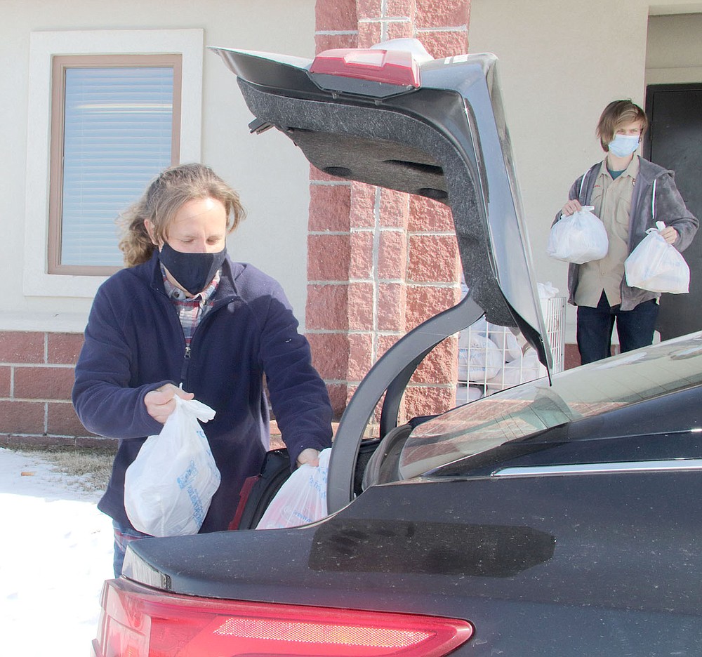 LYNN KUTTER ENTERPRISE-LEADER
Emily Gray, left, and Nick Draper, a member of Boy Scout Troop 555, volunteer Saturday for the monthly drive-through food pantry at Farmington United Methodist Church. Participation was down Saturday, possibly because of the weather, but the church has been serving up to 220 people during its monthly events.