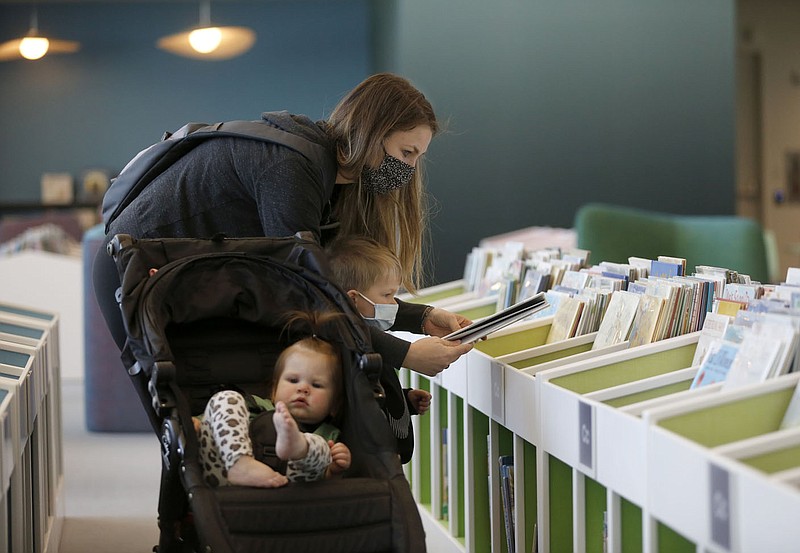 Rachel Sabatini selects books with her son Cooper, 3, and daughter Maisyn, 1, Monday, February 22, 2021, inside the preschool area of the Fayetteville Public Library's new expanded area in Fayetteville. The newly expanded library reopened last month with some sections unavailable to the public because of the covid-19 pandemic. Check out nwaonline.com/210223Daily/ and nwadg.com/photos for a photo gallery.
(NWA Democrat-Gazette/David Gottschalk)