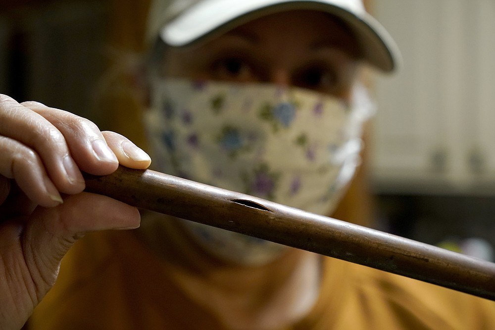 LAST NAME CORRECTIONS AFTER VALERIO, NOT VALERIA - Homeowner Nora Espinoza is holding a piece of broken pipe that handyman Roberto Valerio removed in Dallas on Saturday February 20, 2021.  Espinoza's house suffered multiple burst pipes after winter weather caused freezing temperatures last week.  (AP Photo / Tony Gutierrez)