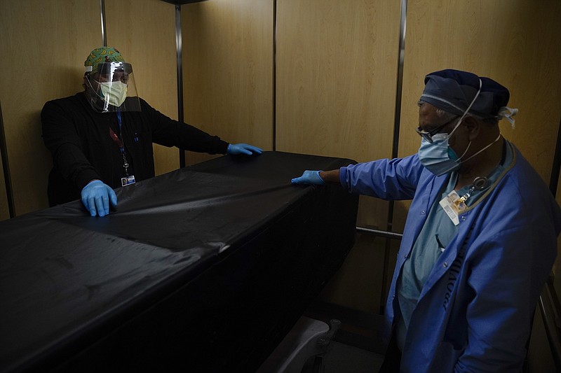 FILE - In this Jan. 9, 2021, file photo, transporters Miguel Lopez, right, Noe Meza move a body of a COVID-19 patient to a morgue at Providence Holy Cross Medical Center in the Mission Hills section of Los Angeles. The U.S. death toll from COVID-19 has topped 500,000 — a number so staggering that a top health researchers says it is hard to imagine an American who hasn't lost a relative or doesn't know someone who died. (AP Photo/Jae C. Hong, File)