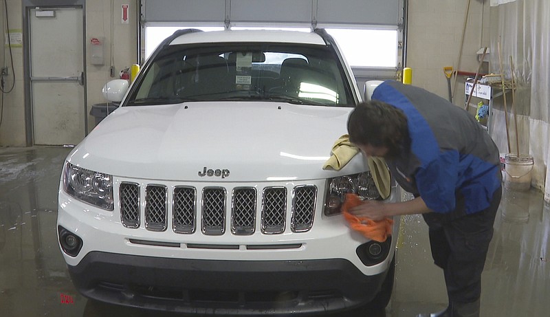 In this image made from video, a worker washes a Jeep inside the service department of a LaFontaine auto dealership in Fenton Township, Mich., Thursday, Jan. 28, 2021. A chain reaction touched off by the coronavirus pandemic has pushed new-vehicle prices to record highs and dramatically driven up the cost of used ones. (AP Photo/Mike Householder)