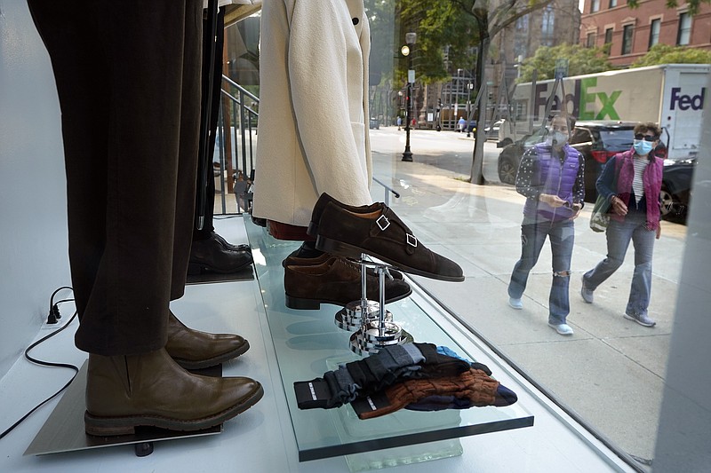 FILE - In this Tuesday, Sept. 15, 2020, file photo, passers-by examine a storefront window in Boston's fashionable Newbury Street shopping district. U.S. consumer confidence dipped slightly in October as a new wave of coronavirus cases began across the country. The Conference Board reported Tuesday, Oct. 27, 2020,  that its consumer confidence index fell to a reading of 100.9, from 101.8 in September. (AP Photo/Steven Senne)