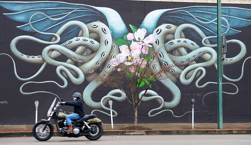 A motorcyclist rides Friday past a mural on Garrison Avenue as rain falls in downtown Fort Smith. The mural was painted by Puerto Rican artist Ana Maria Ortiz and is a part of the Fort Smith Unexpected Project that began in 2015 as an effort to revitalize the city's downtown.
(NWA Democrat-Gazette/Andy Shupe)