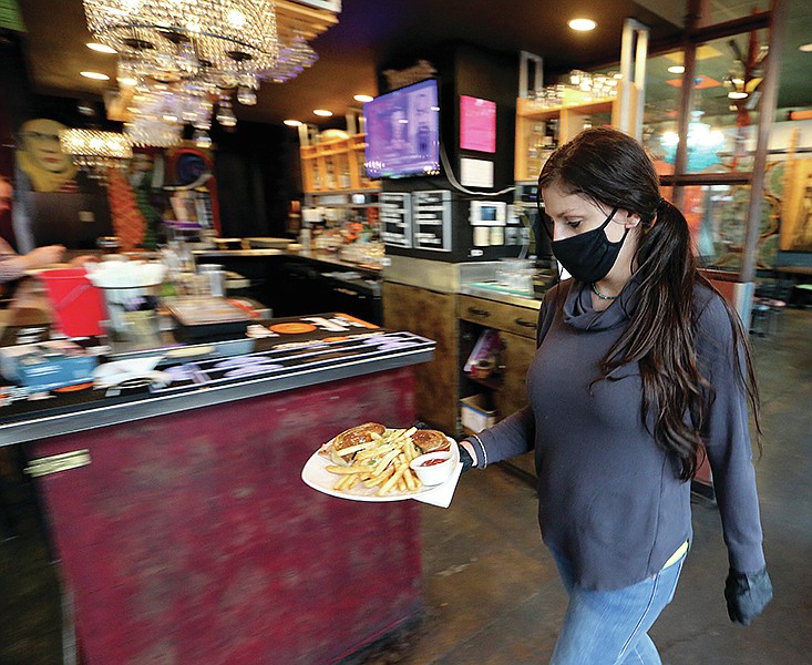 Manager Kim Gatlin delivers an order to a customer on Friday, Feb. 26, 2021, at Dizzy's Bistro in Little Rock. Gov. Asa Hutchinson announced on Friday that restaurant capacity limit restrictions have been changed to guidelines. 
(Arkansas Democrat-Gazette/Thomas Metthe)