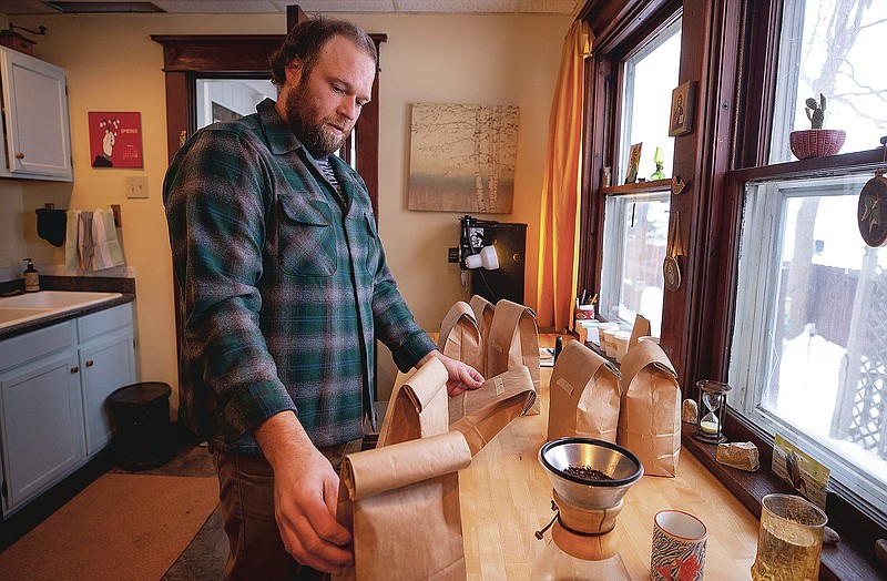 Erik Johnson sorts through the bags of his previously roasted batches of beans, Wednesday, Feb. 10, 2021, in Waverly, Iowa. Along with his wife, Becky, the pair are sharing their creations with other coffee lovers at Thinkwell, an online ordering system where customers can purchase customized coffee beans.  (Chris Zoeller/Globe-Gazette via AP)