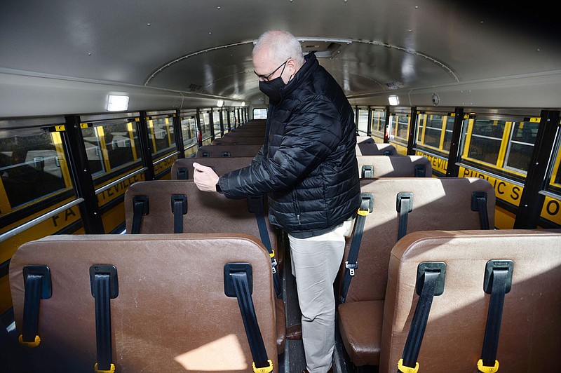 Mike McClure, director of transportation services for Fayetteville Public Schools, demonstrates Friday, Feb. 5, 2021, the seat belts on one of the districtâ€™s busses at the district transportation facility in Fayetteville. Seat belts are present on many but not all busses in Northwest Arkansas. Visit nwaonline.com/210209Daily/ for today's photo gallery. 
(NWA Democrat-Gazette/Andy Shupe)