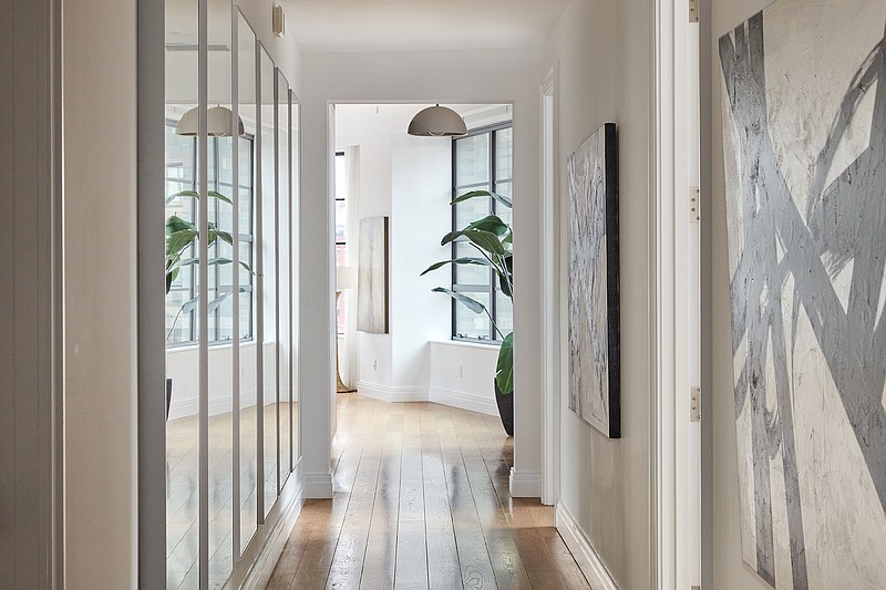 A gallery wall of mirrors reflects wall art down a long hallway.  (TNS)