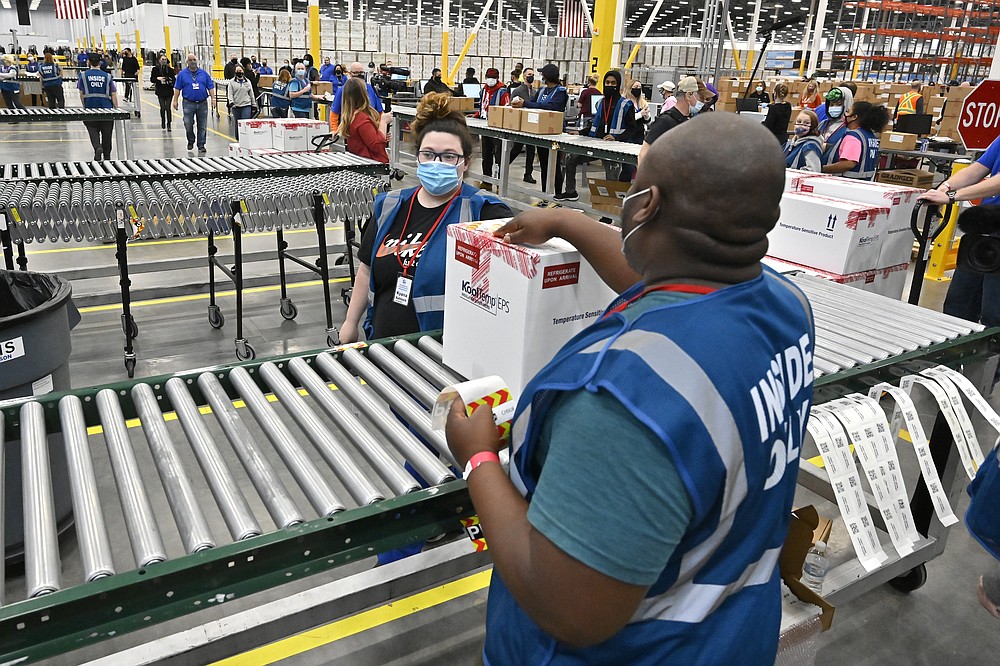 The first box containing the Johnson & Johnson COVID-19 vaccine heads down the conveyor to an awaiting transport truck at the McKesson facility in Shepherdsville, Ky., Monday, March 1, 2021. (AP Photo/Timothy D. Easley, Pool)