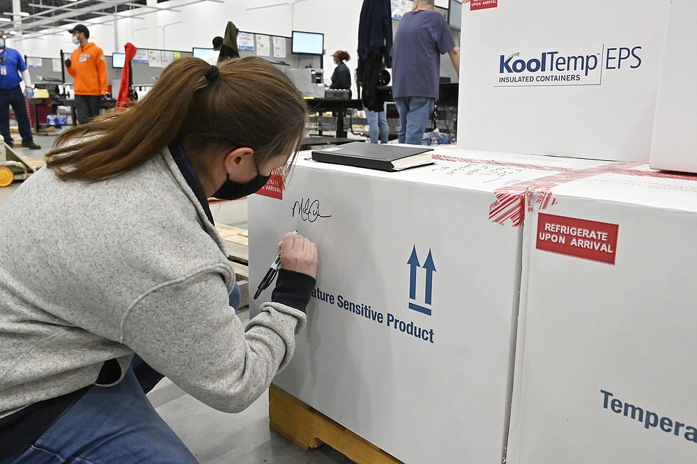 Melissa Owens, operations plant manager for the McKesson Corporation, signs the first shipping box of the Johnson & Johnson COVID-19 vaccine at the McKesson facility in Shepherdsville, Ky., Monday, March 1, 2021. (AP Photo/Timothy D. Easley, Pool)