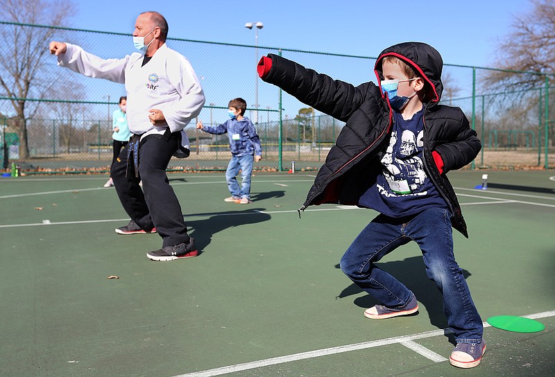 Grey Spicer follows the instructions of Randy Edwards, with Fayetteville Martial Arts, Tuesday as he teaches an introduction to Taekwondo class during the Yvonne Richardson Community Center Homeschool Physical Education Spring 2021 class at Walker Park. The class is held on Tuesday and Thursday and will offer a variety of activities in different parks throughout the city. 
(NWA Democrat-Gazette/David Gottschalk)