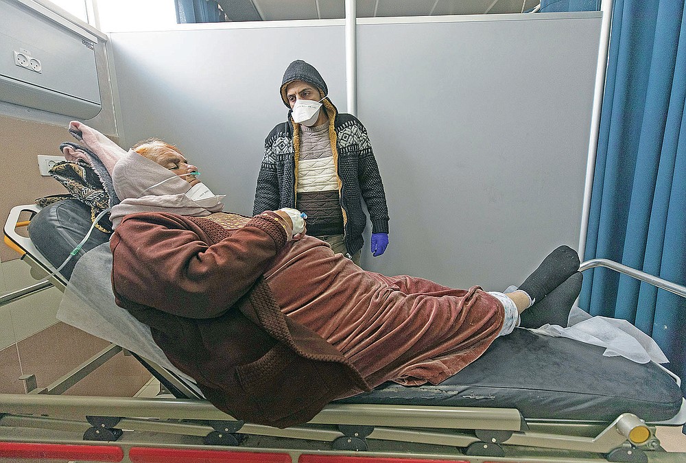 Ibrahim Abu Safiya attends to his mother who is infected with COVID-19 while she is under medical observation at the emergency unit, of the Palestine Medical Complex, in the West Bank city of Ramallah, Tuesday, March 2, 2021. (AP Photo/Nasser Nasser)