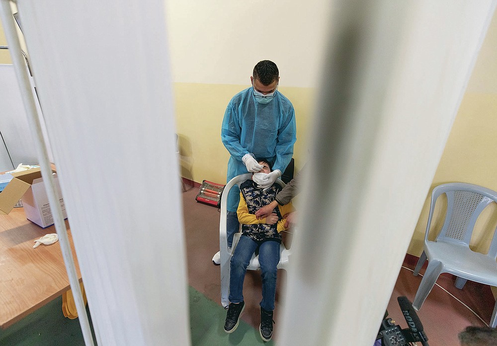 A health care worker takes a nasal swab sample from a Palestinian child at a COVID-19 testing center, in the Palestine Medical Complex, in the West Bank city of Ramallah, Tuesday, March 2, 2021. (AP Photo/Nasser Nasser)