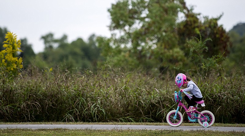 Haley Relano, 4, rides her bike with her family in Two Rivers Park on Sunday, Oct. 18, 2020. (Democrat-Gazette file photo/Stephen Swofford)