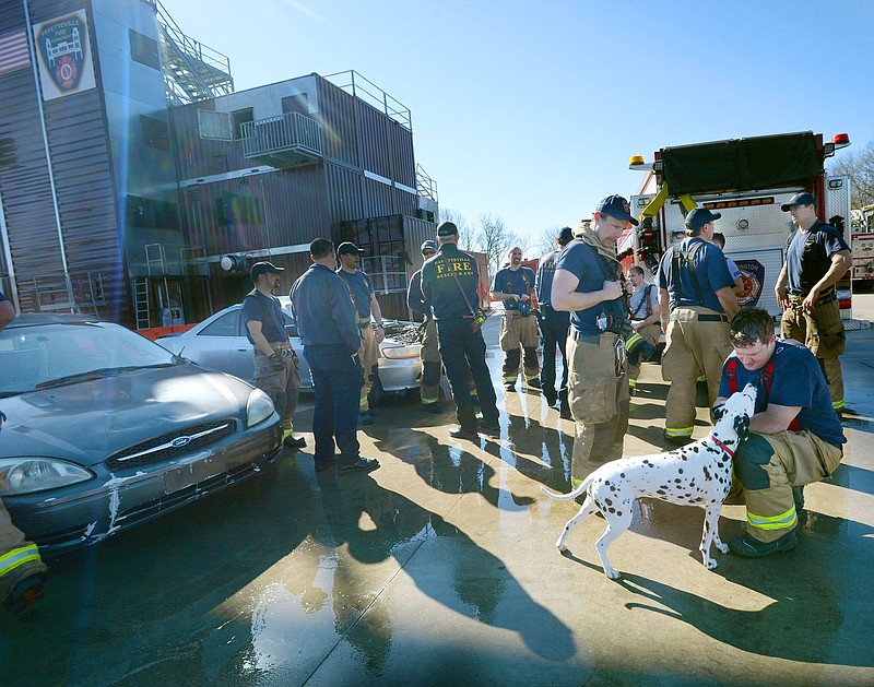 Brice Hall (from right), a firefighter with the Fayetteville Fire Department, pets Ember, a Dalmatian owned by Fayetteville firefighter Martin Striefler Wednesday at the conclusion of a multi-level fire training exercise at the Fayetteville Fire Department’s training facility in Fayetteville. Farmington and Fayetteville partnered in the exercise that continues Friday. 
(NWA Democrat-Gazette/Andy Shupe)