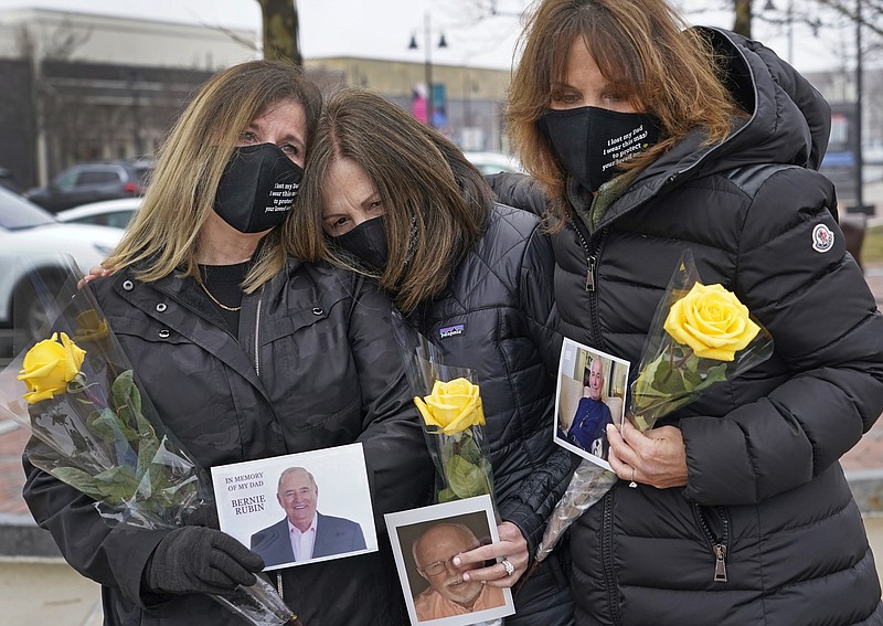 The Associated Press
From left, Michelle Pepe, Lisa Post Mazerolle and Jill Federman hold photos of each of their fathers as they mourn Monday in Lynnfield, Mass. When artist Kristina Libby started the Floral Heart Project to give the survivors of COVID-19 victims places to mourn, she was thinking of people like these three woman who lost their fathers in April, 2020 and who were unable to see them in their last moments.