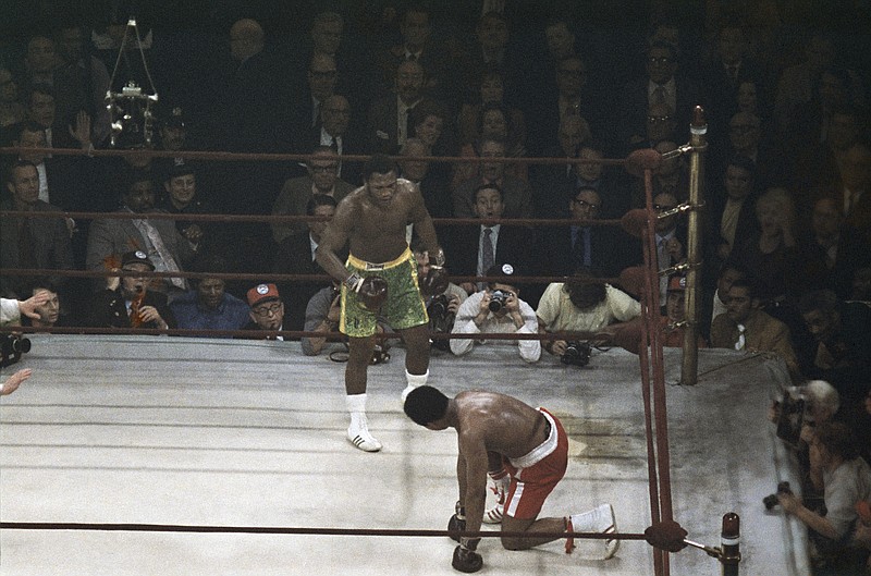 Boxer Muhammad Ali looks up towards Joe Frazier, center, during a March 8, 1971, title fight at Madison Square Garden in New York. - Photo by The Associated Press