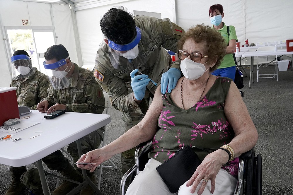FILE - In this March 3, 2021, file photo, In this Loida Mendez, 86, gets the first dose of the Pfizer COVID-19 vaccine from U.S. Army medic Luis Perez, at a FEMA vaccination site at Miami Dade College in North Miami, Fla. Thousands of older Americans are spending hours online or enlisting their grandchildren's help to sign up for a COVID-19 vaccine. An untold number of older people are getting left behind in the desperate dash for shots because they are too frail, overwhelmed, isolated or poor to navigate a system that favors healthier individuals with more resources. (AP Photo/Marta Lavandier, File)