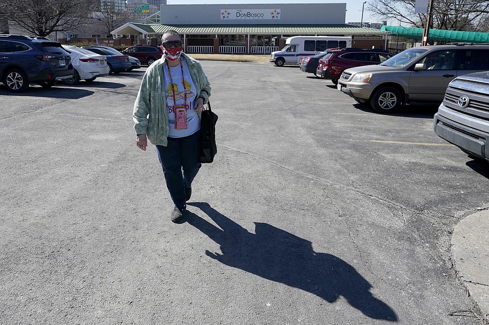 Pat Brown walks away from the Don Bosco Senior Center in Kansas City, Mo., Wednesday, March 3, 2021. Brown knows she needs the vaccine because her asthma and diabetes put her at higher risk of serious COVID-19 complications. But Brown hasn’t attempted to schedule an appointment and didn’t even know if they were being offered in her area yet; she says she is too overwhelmed. (AP Photo/Orlin Wagner)