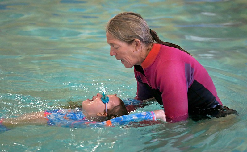 Anita Parisi, a coach with the AquaHawgs, instructs Charlee Hale, 7, Friday how to roll for a breath during a swimming lesson at the Jones Center in Springdale. The Jones Center offers lifeguard training, swimming programs and swimming lessons. Additional information can be found at thejonescenter.net. Check out nwaonline.com/210306Daily/ and nwadg.com/photos for a photo gallery.
(NWA Democrat-Gazette/David Gottschalk)