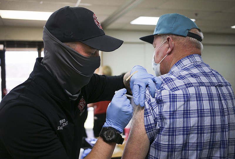 Bella Vista Fire EMS Chaz Harmon (from left) administers a vaccine to Kevin Fields of Bella Vista, Thursday, March 4, 2021 at Riordan Hall in Bella Vista. The Bella Vista Fire Department with the help of volunteers held a vaccine clinic for people in Phase 1-B. They planned 1,200 first doses for the one-day event. Check out nwaonline.com/210305Daily/ for today's photo gallery. 
(NWA Democrat-Gazette/Charlie Kaijo)