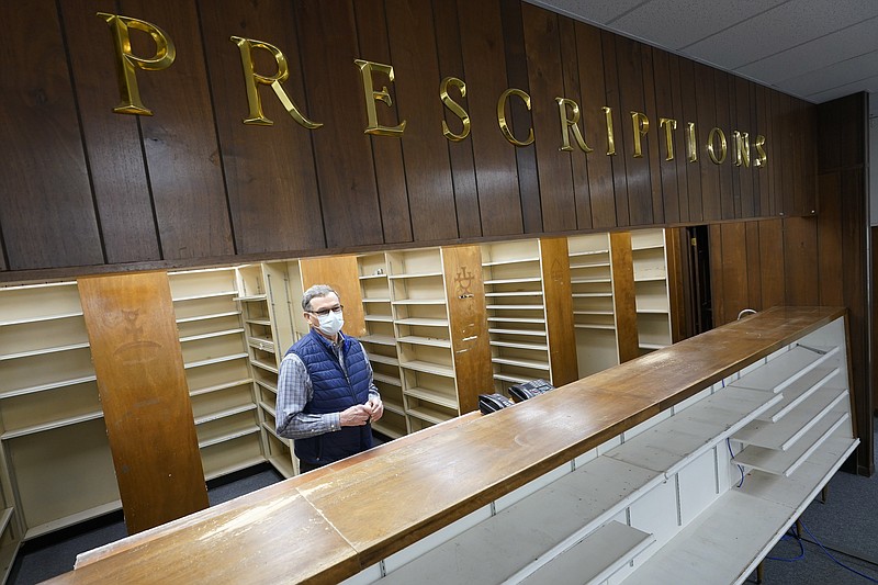 Retired pharmacist, Russell Alan Garner, stands behind the counter in his empty store in Wakefield, Va., Tuesday, Feb. 9, 2021. Getting the coronavirus vaccine has been a challenge for rural counties in the U.S. that lack medical facilities such as a pharmacy or a well-equipped doctor's office. (AP Photo/Steve Helber)