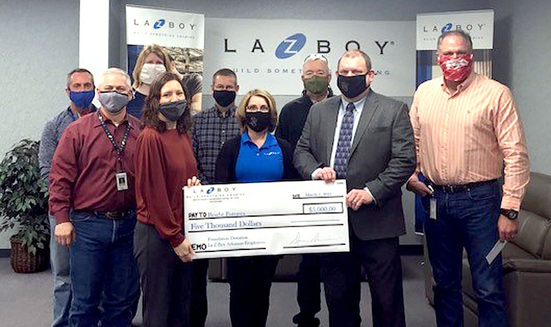 Photo submitted
La-Z-Boy presents a $5,000 check to Bright Futures Siloam Springs on Friday to help replenish the supplies lost to water damage from flooding caused by burst pipes during the unusually cold weather in February. Pictured are (front left) Tiffany Hansen, Bright Futures coordinator; Audra Farrell, La-Z-Boy human resources manager; Jody Wiggins, school superintendent; Daren Davison, La-Z-Boy general manager; (back left) Dean Graham, La-Z-Boy controller; Matt Bevis, La-Z-Boy CI and facilities manager; Cathy Simkins, La-Z-Boy supply chain manager; Jim Larson, La-Z-Boy EHS manager; and Mike Wilmon, La-Z-Boy production manager.