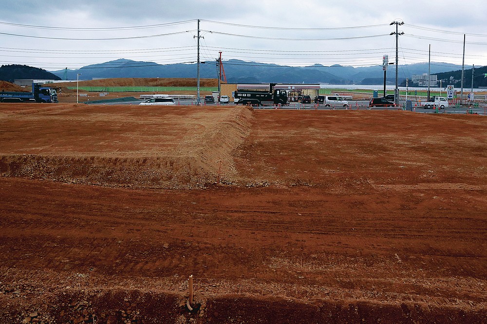 This March 5, 2016, file photos, trucks and cars drive through the flat town of Minamisanriku in Miyagi Prefecture in northern Japan, almost five years after the tsunami.  (AP Photo / Eugene Hoshiko, File)