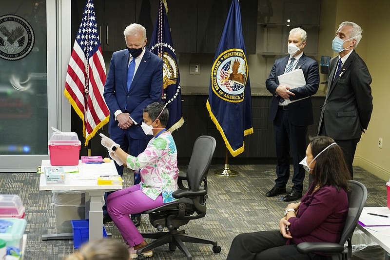 President Joe Biden, standing left, visits a COVID-19 vaccination site and watches Pharmacist Deepika Duggineni, seated, prepare a vaccine, with Secretary of Veterans Affairs Denis McDonough, right, and White House COVID-19 Response Coordinator Jeff Zients, center, at the VA Medical Center in Washington, Monday, March 8, 2021. (AP Photo/Patrick Semansky)