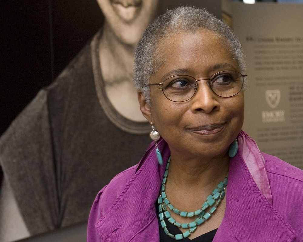 FILE - In this April 23, 2009 file photo, Alice Walker stands in front of a picture of herself from 1974 as she tours her archives at Emory University, in Atlanta.  Walker and The New York Times are drawing fire after she praised an author who critics say is a conspiracy theorist who expresses anti-Semitism. In an interview in Sunday’s “By The Book” column, the author of “The Color Purple” said David Icke’s 1995 book, “And The Truth Shall Set You Free,” is on her nightstand. A New York Times spokesperson says the column is not a list of recommendations from its editors. (AP Photo/John Amis, File)