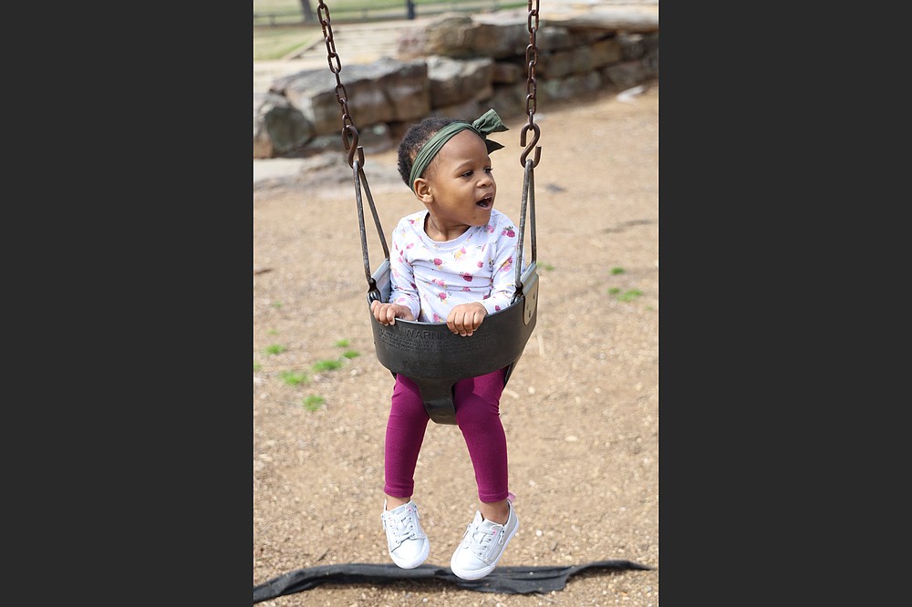 Mauria, 2, a child awaiting adoption, plays on the swing at Little Rock’s War Memorial Park. The covid-19 pandemic presented a challenge to agencies that help Mauria and other wards of the state find forever families. (Special to the Democrat-Gazette/Dwain Hebda)