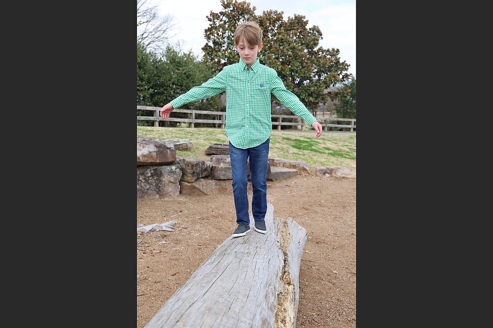 Isaiah, 9, a child awaiting adoption, walks a log at War Memorial Park. Statistics from the Arkansas Department of Human Services’ Division of Children and Family Services show that the number of children in foster care at the end of 2020 grew to 4,663, with average discharges to permanency lowered by more than 40 kids per month and discharges to reunification down 14 children per month, compared to 2019. Adoptions were also down year over year. (Special to the Democrat-Gazette/Dwain Hebda)