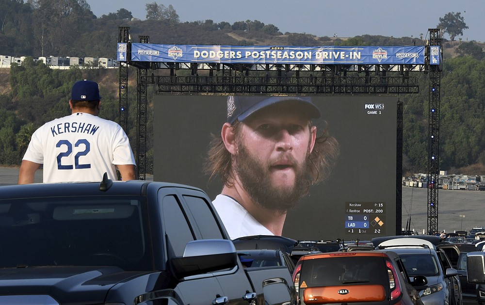 FILE - A fan watches the World Series Game 1 between the Tampa Bay Rays and the Los Angeles Dodgers in the parking lot of Dodger Stadium in Los Angeles in this Tuesday, October 20, 2020, file photo. Sports events held amid the coronavirus pandemic have become a whole different sort of spectacle when it comes to spectators.(Keith Birmingham/The Orange County Register via AP, File)
