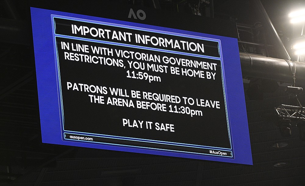FILE - An electronic signboard on Rod Laver Arena reminds patrons about the lockdown start time during the third round match between Serbia's Novak Djokovic and United States' Talyor Fritz at the Australian Open tennis championship in Melbourne, Australia, in this Friday, Feb. 12, 2021, file photo. Sports amid the pandemic became a whole different sort of spectacle, especially when it came to spectators — often with zero, sometimes with some and, in at least one instance at a Grand Slam tennis tournament, starting a match with fans in the seats yet finishing it with none present. (AP Photo/Andy Brownbill, File)