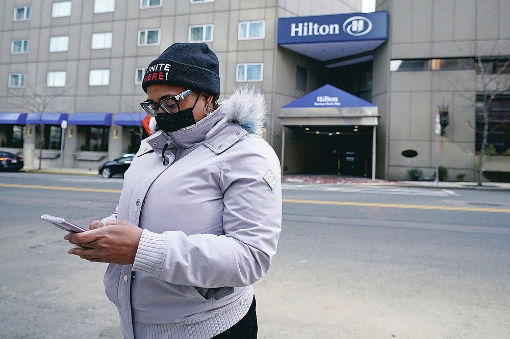 Hotel housekeeper Esther Montanez looks at her cell phone outside the Hilton Back Bay, Friday, March 5, 2021, in Boston. Montanez refuses to give up hope of returning to her cleaning job at the hotel, which she held for six years until being furloughed since March 2020 due to the COVID-19 virus outbreak. The single mother cannot bear the idea of searching for work that will almost certainly mean earning near the minimum wage.   (AP Photo/Charles Krupa)