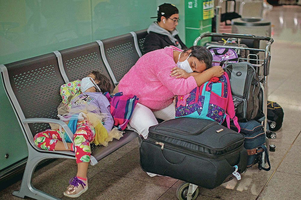 FILE - In this March 12, 2020, file photo, passengers rest at the Barcelona airport, Spain. President Donald Trump, who had downplayed the coronavirus for weeks, suddenly struck a different tone, announcing strict rules on restricting travel from much of Europe to begin this weekend. (AP Photo/Emilio Morenatti, File)