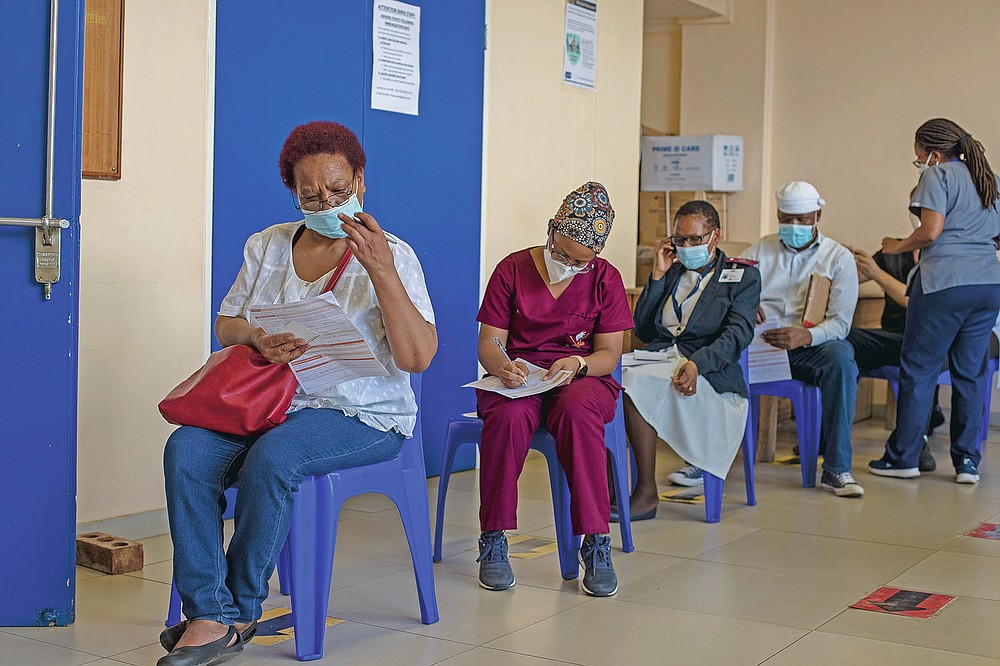Maggie Sedidi, left, a 59-year-old nurse at Soweto's Chris Hani Baragwanath hospital, reads a medical questioner before receiving her dose of the Johnson & Johnson COVID-19 vaccine at a vaccination center in Soweto, South Africa, Friday, March 5, 2021. Sedidi is optimistic: "By next year, or maybe the year after, I really do hope that people will be able to begin returning to normal life." (AP Photo/Themba Hadebe)