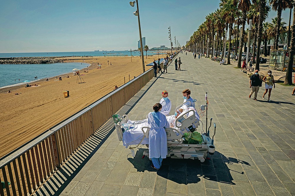 FILE - In this Sept. 4, 2020, file photo, Francisco Espana, 60, is surrounded by members of his medical team as he looks at the Mediterranean sea from a promenade next to the "Hospital del Mar" in Barcelona, Spain. Francisco spent 52 days in the Intensive Care unit at the hospital due to coronavirus, but today he was allowed by his doctors to spend almost ten minutes at the seaside as part of his recovery therapy. (AP Photo/Emilio Morenatti, File)