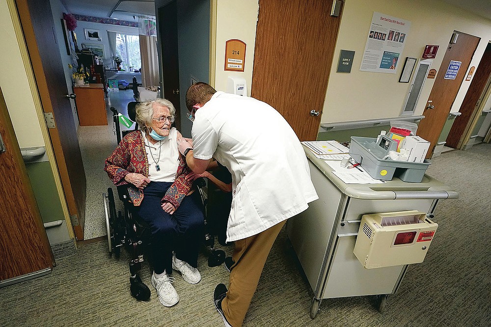 FILE - In this Jan. 8, 2021, file photo, Jean Allen, 96, left, receives the first shot of the Pfizer vaccination for COVID-19, from a Walgreens Pharmacist, right, at Queen Anne Healthcare, a skilled nursing and rehabilitation facility in Seattle. Allen survived catching COVID-19 before she was vaccinated, during a 2020 outbreak of COVID-19 that killed more than a dozen residents and two staff members. (AP Photo/Ted S. Warren, File)