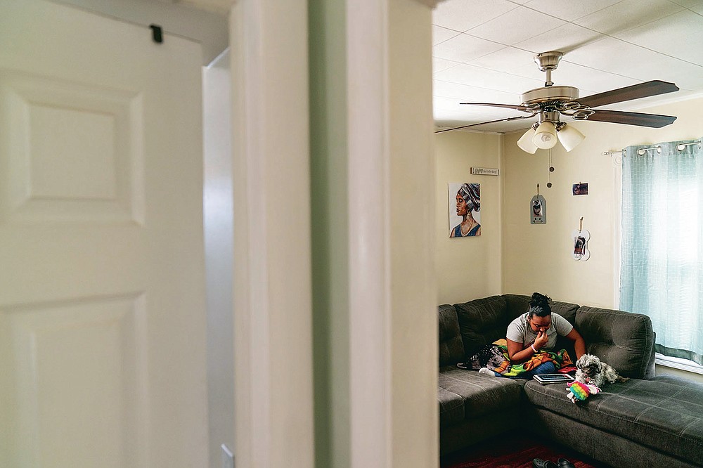 Darelyn Maldonado, 12, sits on the couch with her dog, Lisa, at her home in Pawtucket, R.I., Wednesday, March 3, 2021. Maldonado, a seventh grade student, has been out of in person school for a year since the pandemic began. She feels like she's lost friends over the past year, has missed out on playing softball which she loves and just wants her life to go back to normal. (AP Photo/David Goldman)