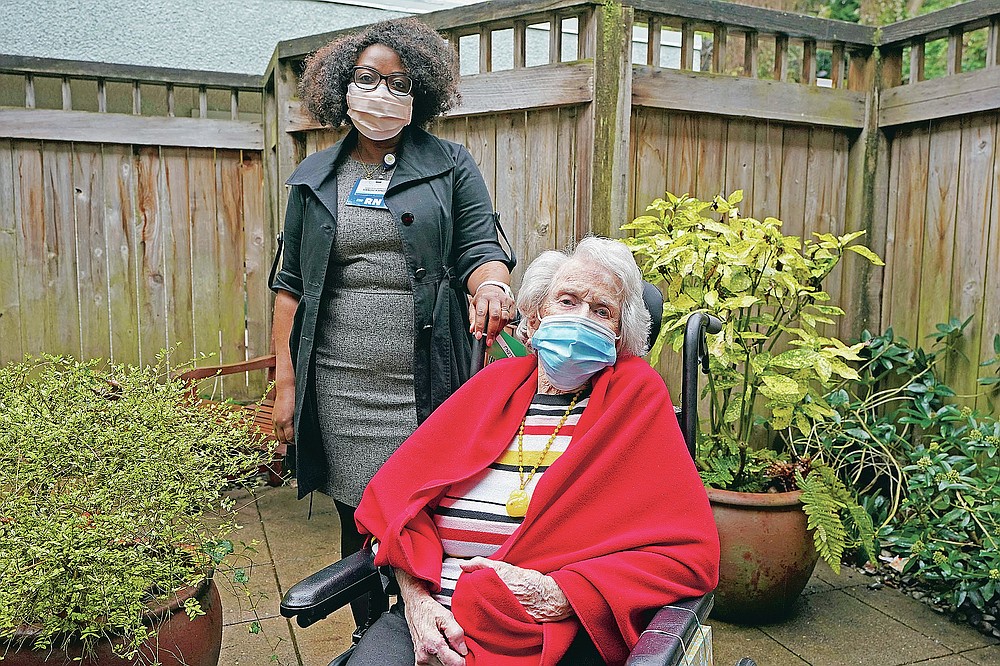 Sangu Kande, left, a nurse at Queen Anne Healthcare, a skilled nursing and rehabilitation facility in Seattle, poses for a photo, Friday, March 5, 2021, with Jean Allen, 96, one of the patients Kande cared for during the past year. Allen was infected and recovered from coronavirus. But 19 of her fellow residents and two beloved staff members died. The deaths trailed off, but the isolation and boredom continue. (AP Photo/Ted S. Warren)