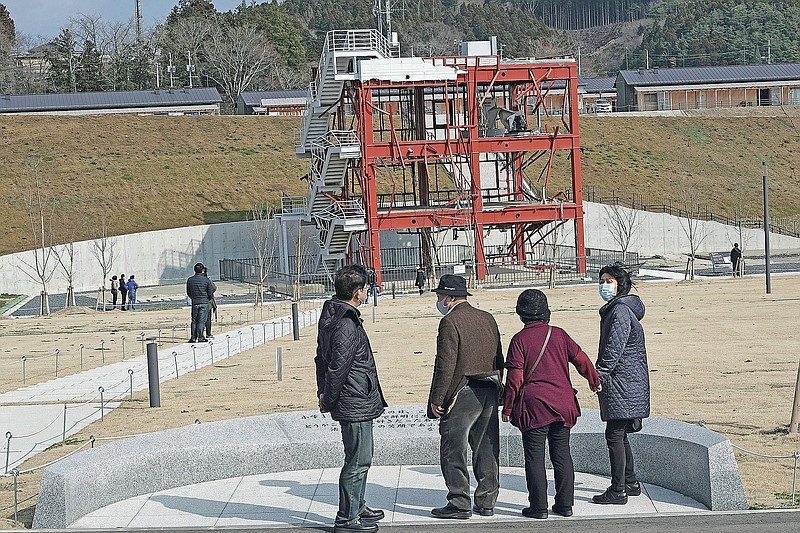Visitors look at the skeleton of the disaster prevention headquarters building where 43 workers died as the March 11, 2011 tsunami washed over it, in Minamisanriku, Miyagi Prefecture, northern Japan, Saturday, March 6, 2021. The three-story building is one of legacies that still stand in northern Japan's coastal towns, 10 years after the earthquake and tsunami that killed more than 18,000 people. (AP Photo/Eugene Hoshiko)
