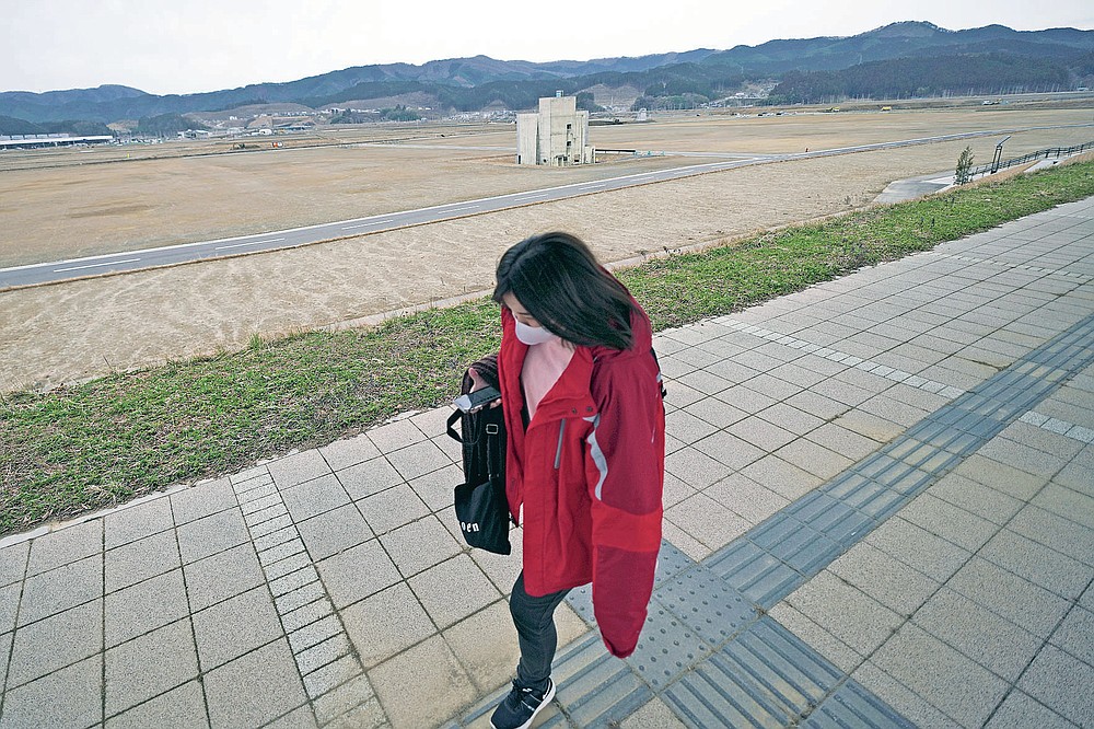 A woman walks past the ruin of a building destroyed by the 2011 tsunami in Rikuzentakata, Iwate Prefecture, Friday, March 5, 2021. In Rikuzentakata more than 1,700 people died by the March 11, 2011 disaster. (AP Photo/Eugene Hoshiko)