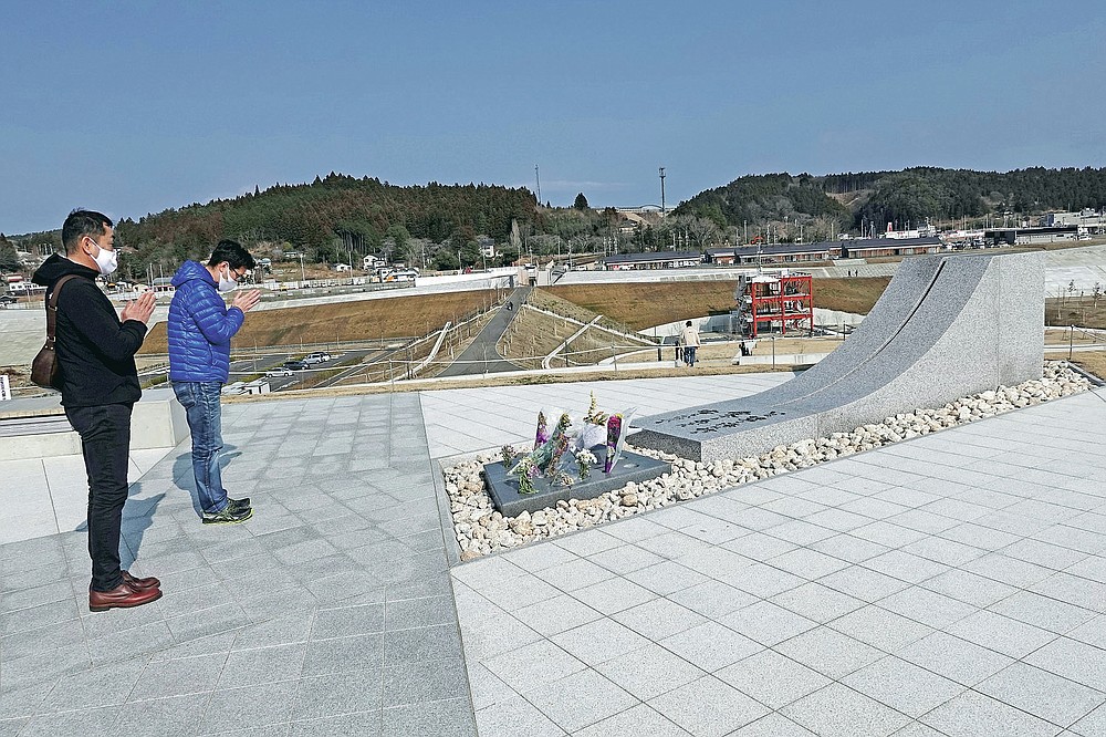Visitors pray for the victims of the 2011 tsunami disaster at the Minamisanriku Memorial Park of Earthquake Disaster in Minamisanriku, Miyagi Prefecture, northern Japan, Saturday, March 6, 2021. The disaster marks the 10th-year anniversary on March 11, 2021. (AP Photo/Eugene Hoshiko)