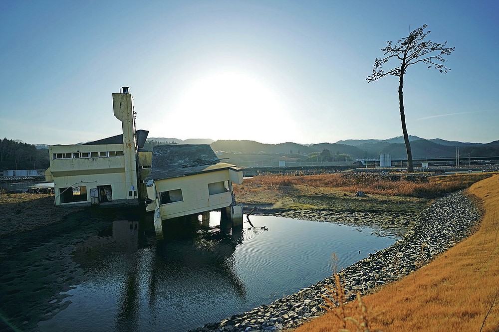 A replica of a lone pine tree that initially survived the 2011 tsunami that flattened the surrounding coastal forest, right, is seen in Rikuzentakata, Iwate Prefecture, northern Japan Thursday, March 4, 2021. The tree, which eventually died of seawater exposure, was known as the "Miracle Pine," and townspeople treated, reinforced and then preserved it as a memorial and symbol of hope for the region. (AP Photo/Eugene Hoshiko)