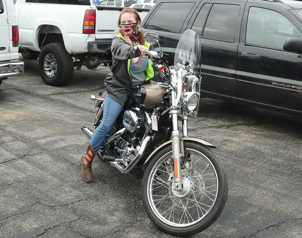 Potential buyer Monica Womack, of Hot Springs, sits on a Harley-Davidson motorcycle up for auction at the 18th Judicial District East Drug Task Force auction at the Bill Edwards Center Friday. - Photo by Richard Rasmussen of The Sentinel-Record